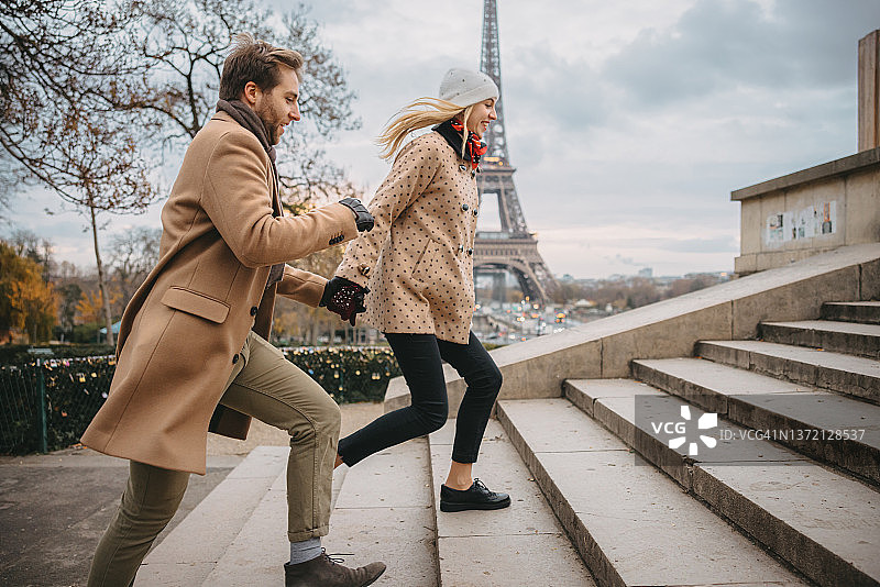 这对浪漫的情侣兴奋地跑着从巴黎的男人公园去看埃菲尔铁塔图片素材