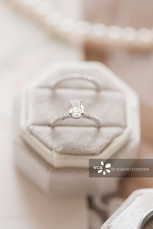 白色的黄金钻石结婚戒指在一个天鹅绒戒指盒在明亮的自然光图片素材