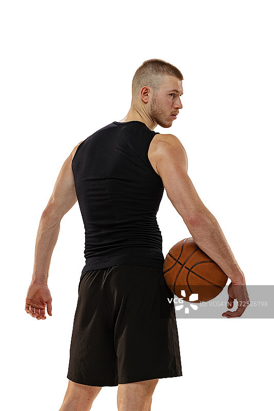 后视图的肌肉男子，篮球运动员站在篮球孤立的白色工作室背景。运动，运动，活动的概念。图片素材