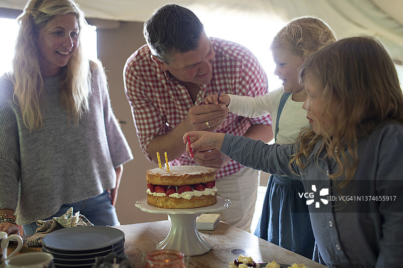 家人用草莓蛋糕和蜡烛庆祝生日图片素材