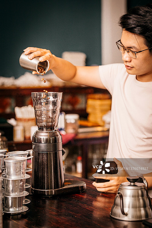 年轻的亚裔男咖啡师，穿着白衬衫，用化学咖啡机煮咖啡图片素材