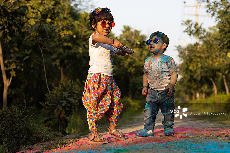 快乐的亚洲印度孩子男孩和女孩享受节日的颜色与胡里彩粉称为古拉尔或范围图片素材
