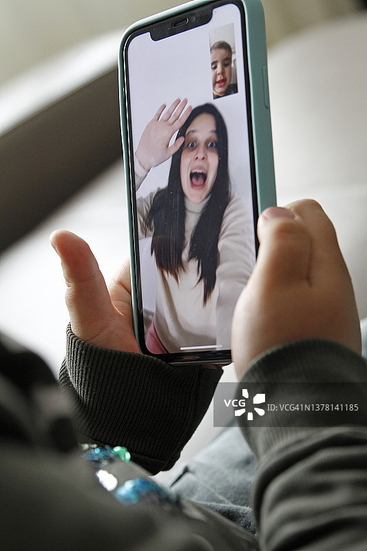 男孩用智能手机和家人视频通话图片素材