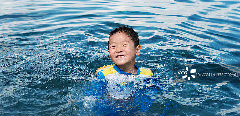 快乐的男孩在游泳池里游泳图片素材