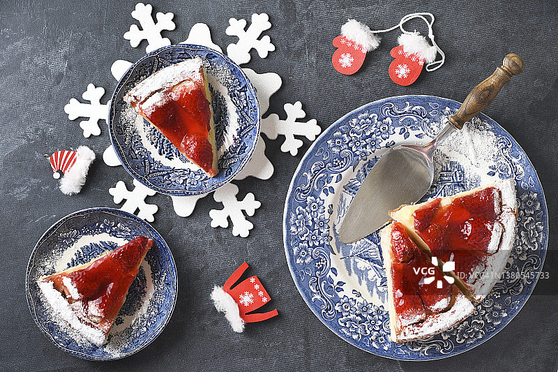 圣诞节红色的草莓派放在蓝色的盘子里，礼物放在红色的盒子里放在桌子上，彩色的食物平铺在白色的针织餐巾上，以雪花的形式，冬天的心情。图片素材