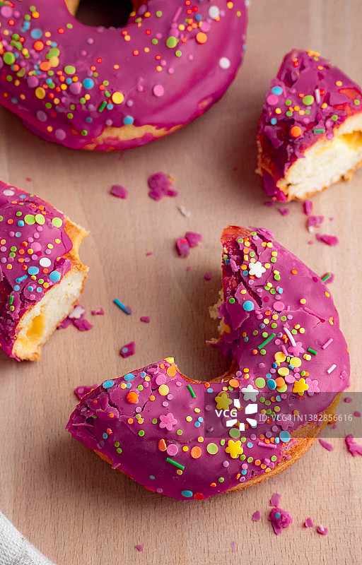 木制的圆甜甜圈上涂着紫罗兰糖霜。糖果的精美排列图片素材
