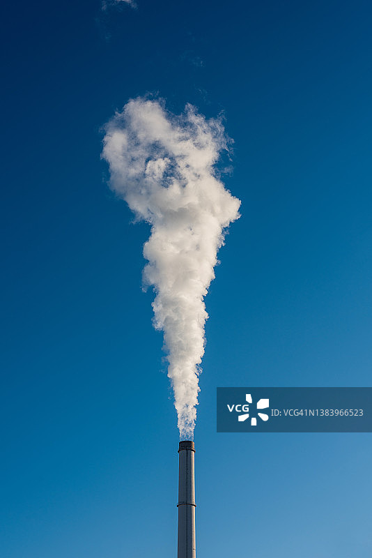 一家燃煤电厂的烟囱正将一吨的蒸汽和温室气体吹向多云的天空。图片素材