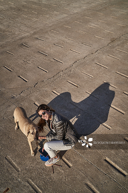 快乐的女人带着狗在街上图片素材