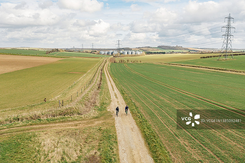无人机拍摄的两个骑自行车的人在英国乡村的碎石小道上图片素材
