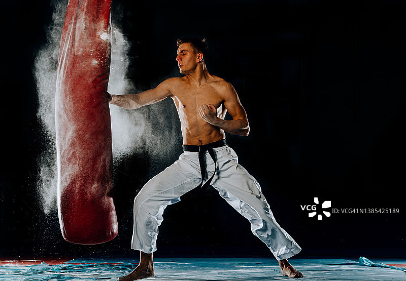 在健身俱乐部，男拳击手正在用沙包进行训练。图片素材