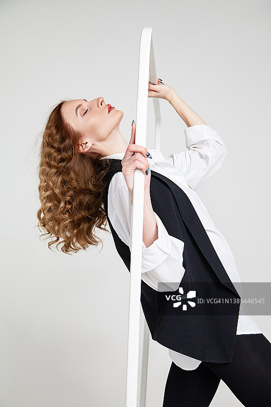时尚的女士站在附近的衣服栏杆对白色的背景图片素材