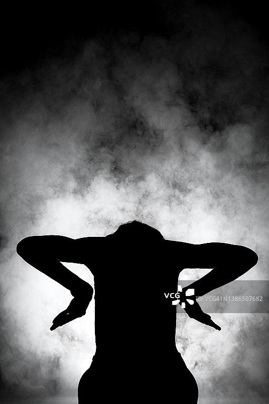 剪影现代芭蕾舞演员摆姿势在黑暗的背景与烟图片素材