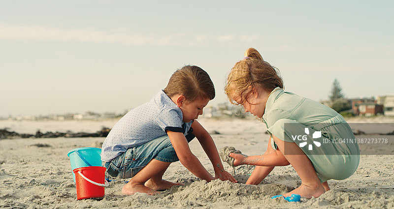 一个小女孩和一个小男孩在沙滩上玩耍图片素材