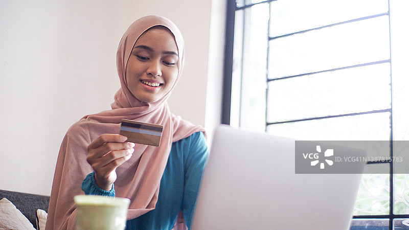 亚洲穆斯林年轻女子戴着头巾，带着笔记本电脑图片素材