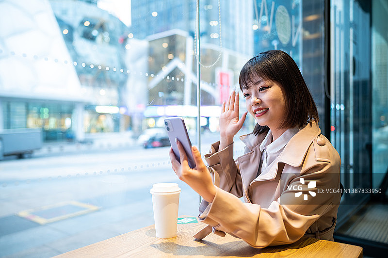 亚洲年轻女子在咖啡店使用智能手机图片素材