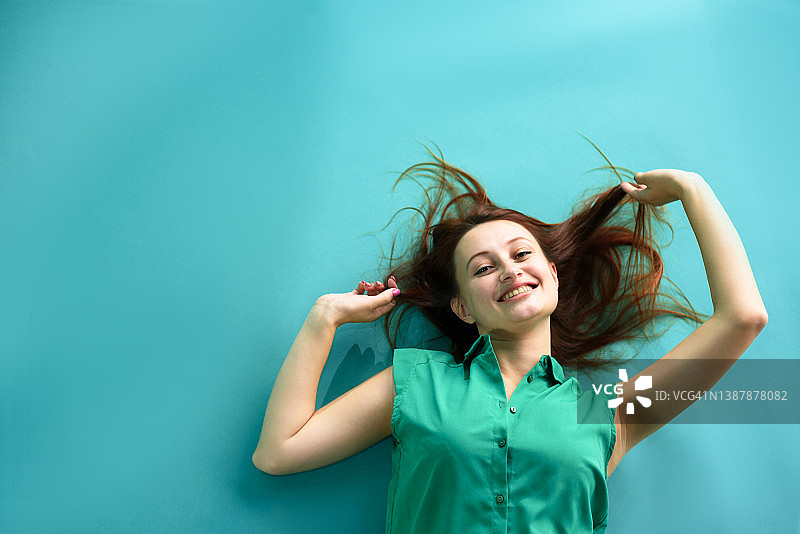 在蓝色背景上快乐的红发年轻女子有趣的脸的特写肖像。本空间图片素材