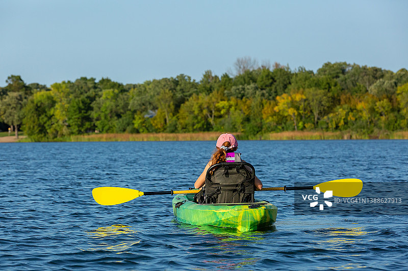 女孩在绿色和黄色皮艇在湖上图片素材