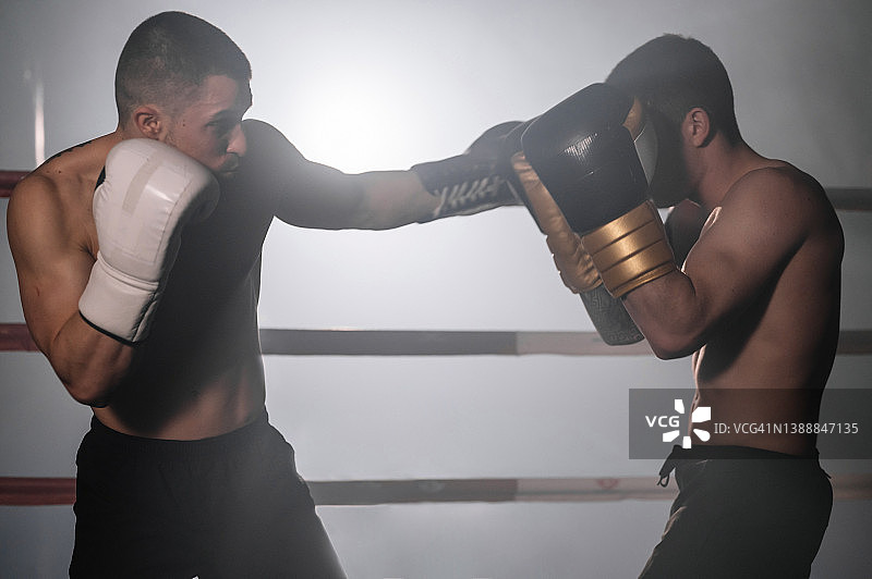两位肌肉发达的综合格斗运动员在擂台上搏击。高质量的摄影。图片素材