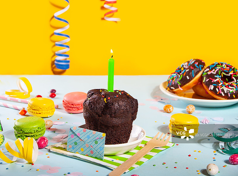 美味的巧克力松饼纸杯蛋糕，背景是生日蜡烛和其他糖果。方的概念图片素材