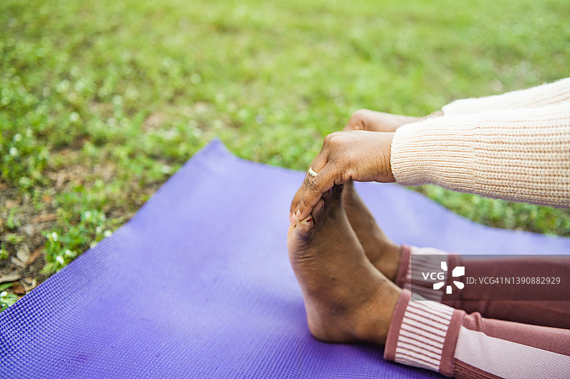 一个黑人妇女在瑜伽姿势中手握脚的特写图片素材
