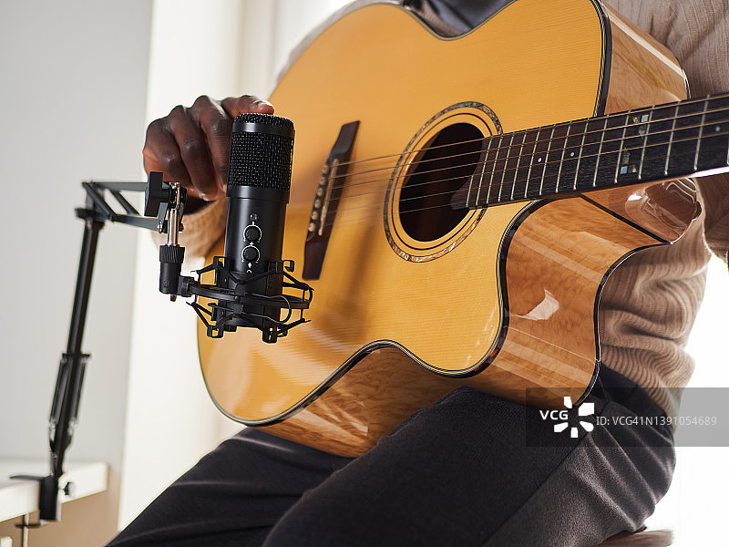一个年轻人在家里一边唱歌一边弹吉他，一边录音图片素材