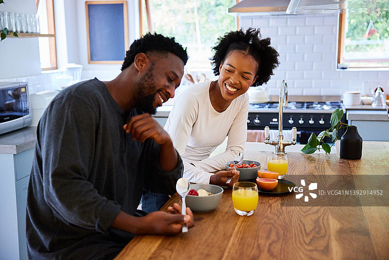 笑着的年轻夫妇在他们的厨房享受健康的早餐图片素材