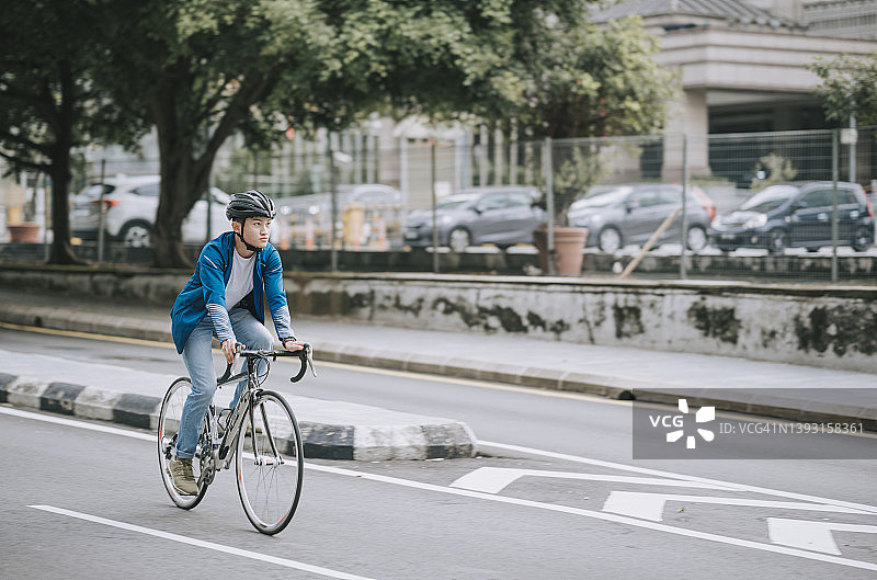 亚洲华人男子在城市的自行车道上骑车，追求可持续的生活方式图片素材