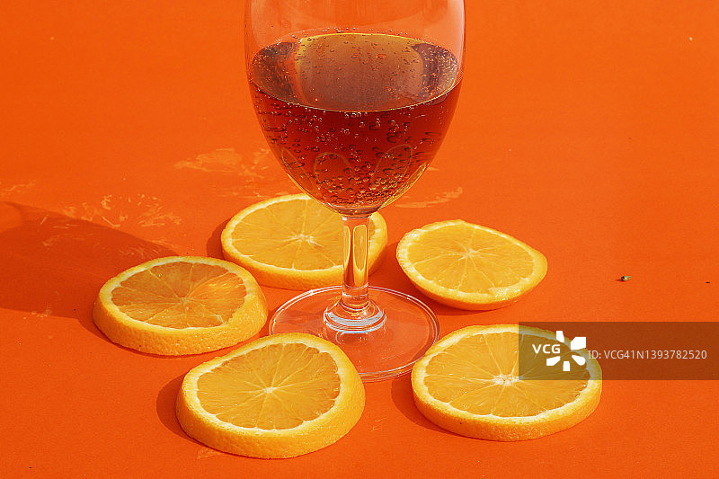 特写的橙色切片和酒杯对橙色的背景。图片素材