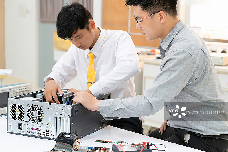 教师肖像教机器人和电子板机器人与青年亚洲大学在计算机实验室在科学教室学习编程图片素材
