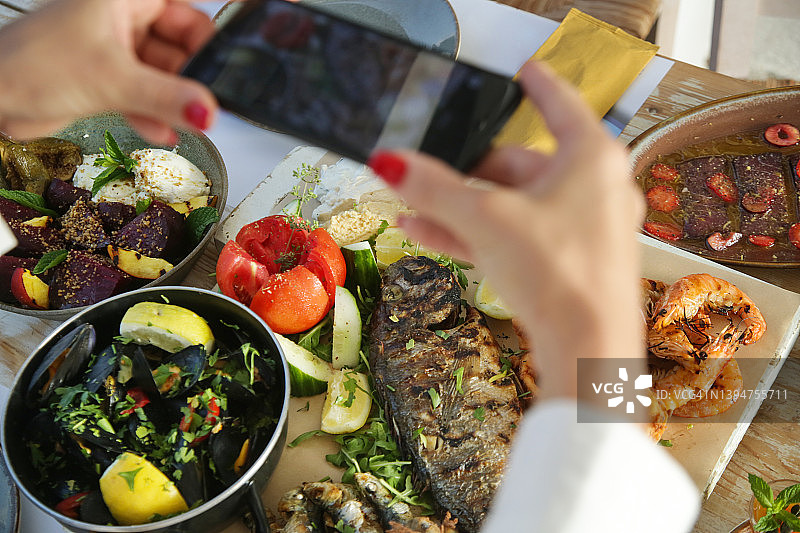 女子在餐厅用餐前用智能手机拍食物照片图片素材