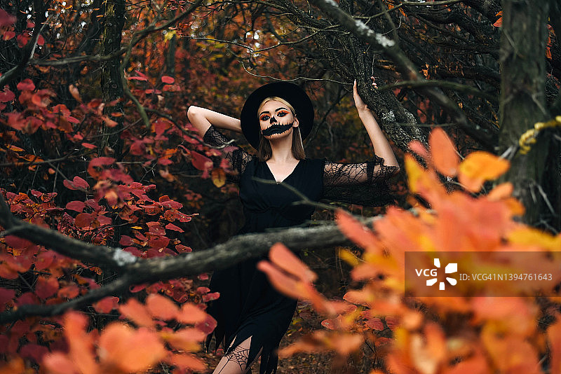 美丽的女孩在万圣节化妆的背景，秋天的森林。万圣节。秋天的森林。图片素材