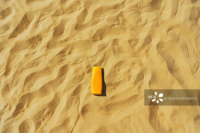 空旷的沙滩上，夏天的大海和防晒霜瓶子。图片素材