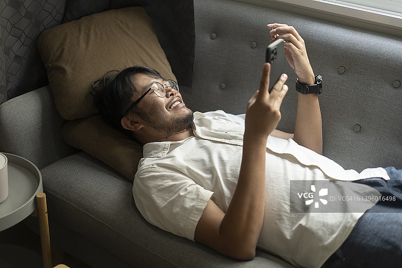 积极情绪亚洲青年自由职业者(数字游牧民)的快乐使用手机和笔记本电脑在家里工作家庭生活图片素材