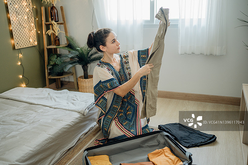 女人在假期里在家收拾行李准备旅行。图片素材