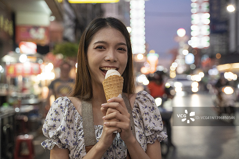 夏日的泰国街头，微笑的女人手拿冰淇淋。图片素材