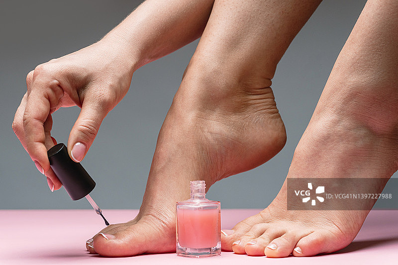 女性脚与美丽的法国足疗。在脚趾甲上涂粉红色指甲油的女人。图片素材