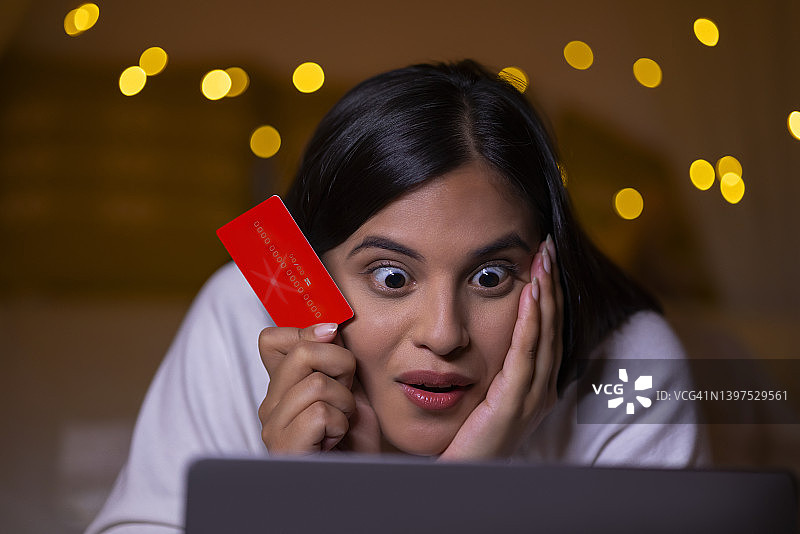 印度漂亮女孩在网上购物时用借记卡好奇地看着笔记本电脑图片素材