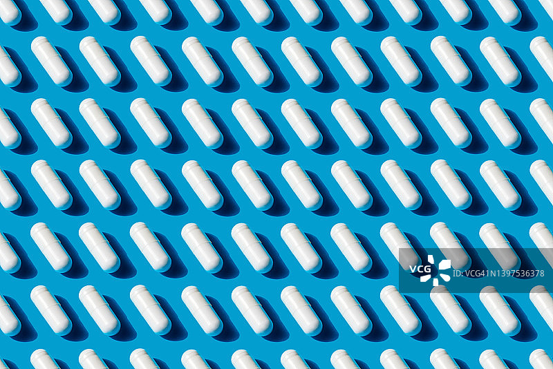 流行艺术图案白色药丸胶囊孤立在蓝色背景图片素材