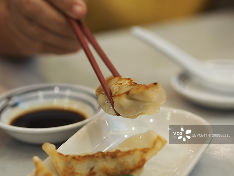 用筷子夹起饺子，把饺子舀到蘸酱里图片素材