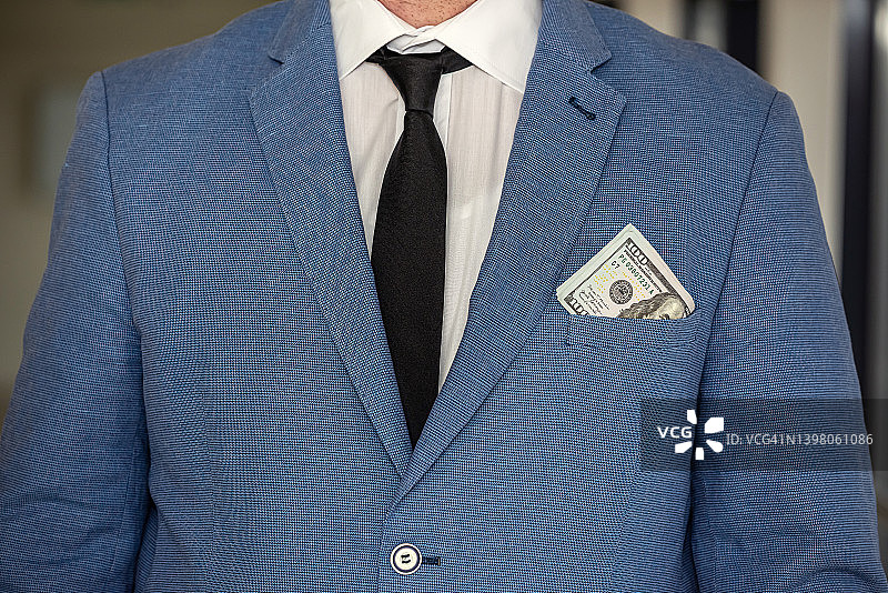英俊的年轻商人穿着西装里的时髦夹克，身上带着一大笔钱。图片素材
