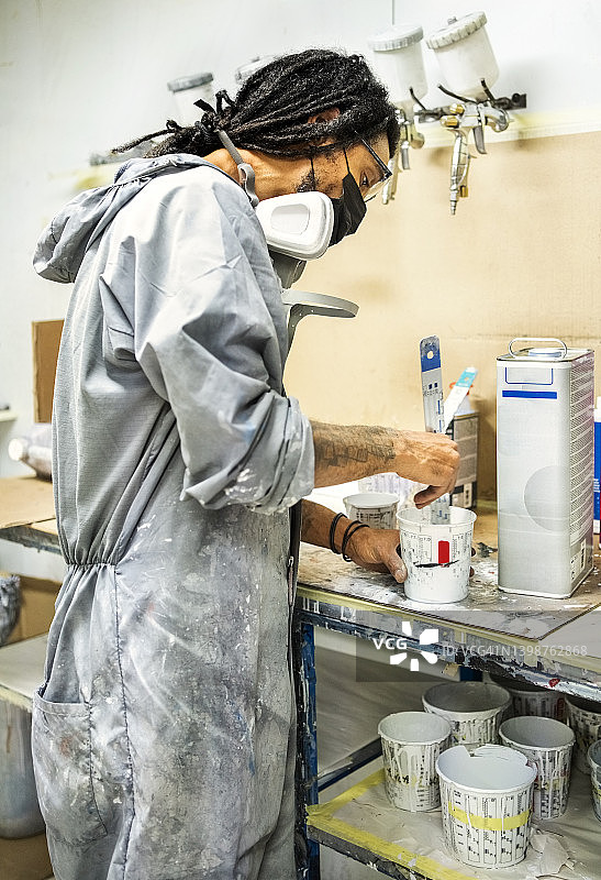汽车油漆工在汽车修理店的塑料容器中混合油漆图片素材