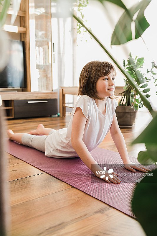 儿童瑜伽姿势。女孩在家在线学习瑜伽。体育生活方式。体育在孩子们的生活中图片素材