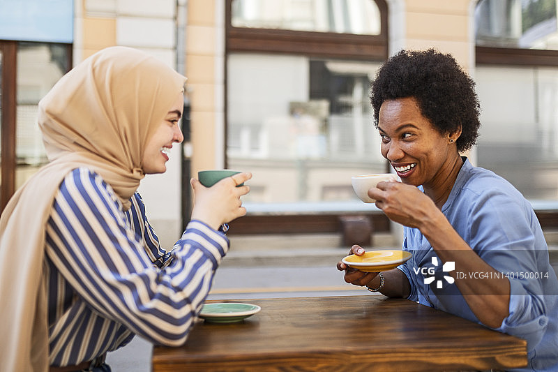 一位戴着希贾布的妇女在喝咖啡的时候和她的非洲朋友聊天图片素材