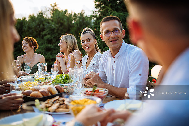 夏天，一群人围坐在美丽的花园里，吃着健康的食物图片素材