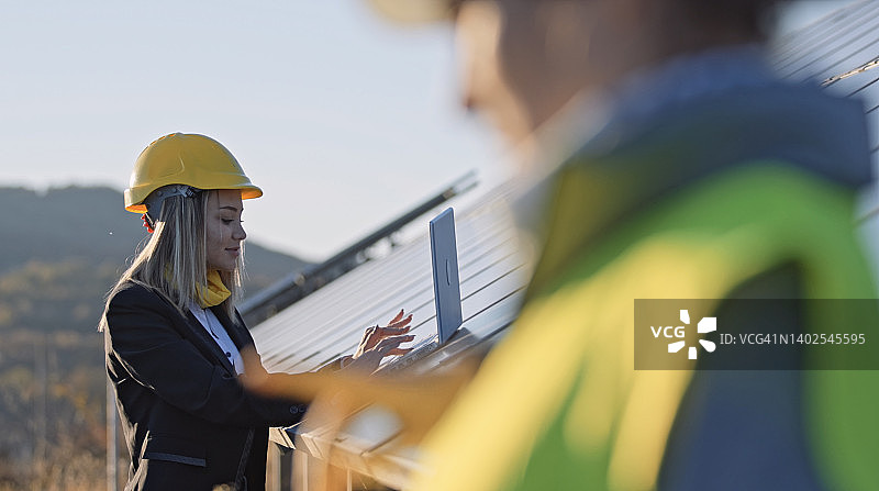 在太阳能发电厂工作的女工程师。团队合作。可再生能源系统。太阳能城市。图片素材
