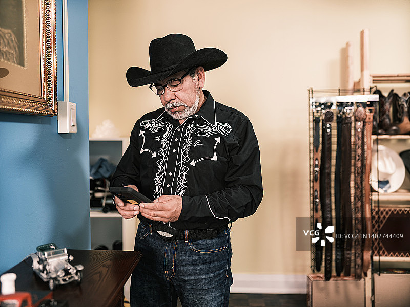 成熟的拉丁男子打扮成墨西哥牛仔使用手机图片素材
