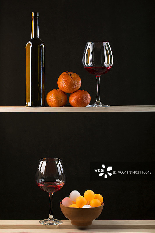 静物与彩色球在一个盘子，瓶子，酒杯的酒和橘子图片素材