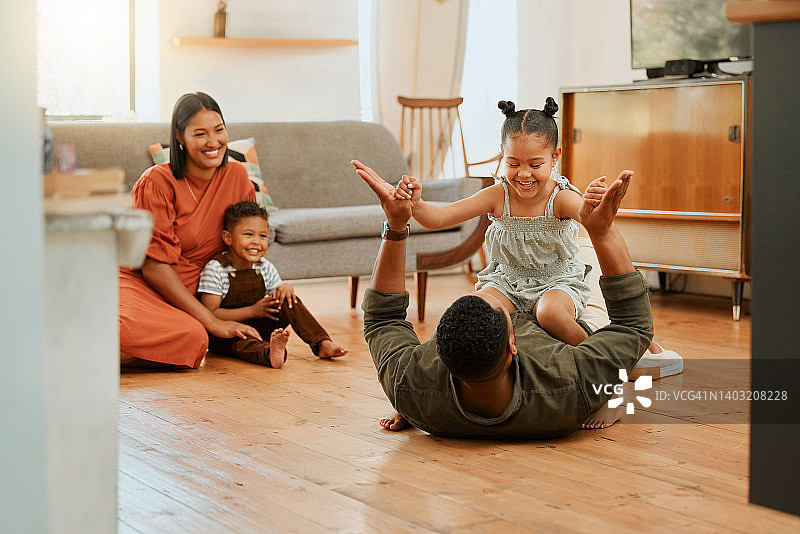 一个幸福的混合种族四口之家在休息室放松，一起玩耍。热爱黑人家庭的孩子们在家里的地板上玩有趣的游戏图片素材