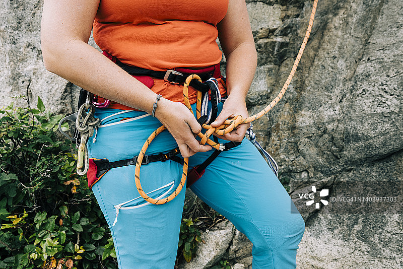 一名攀岩者将一根攀爬绳系在安全带上的特写图片素材