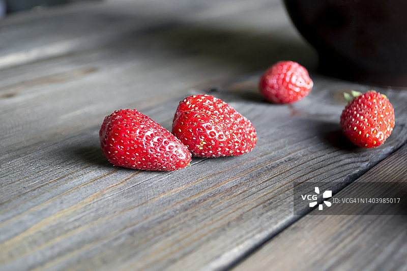 没有尾巴的熟草莓放在木桌上。成熟的浆果。夏天草莓丰收。两个浆果。图片素材